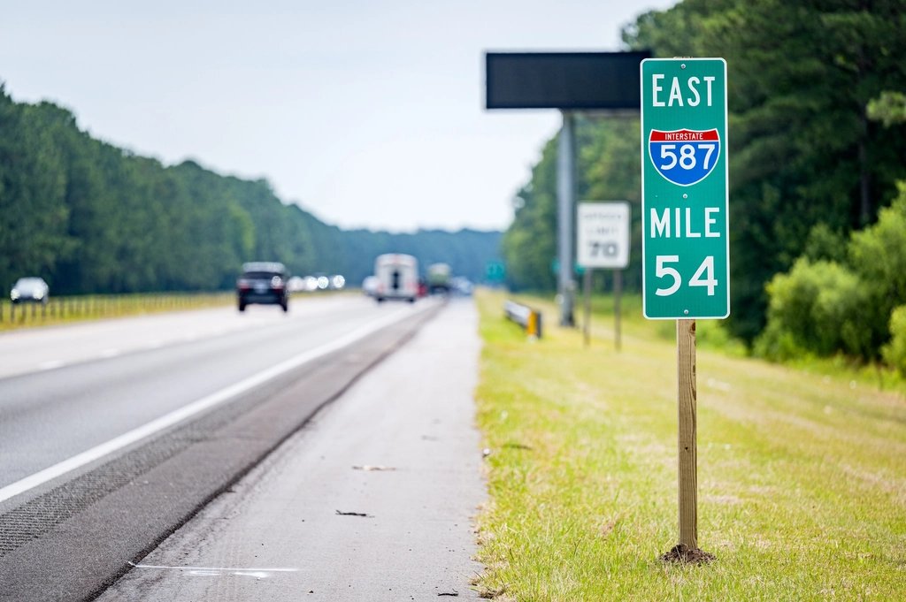 Cars travel past an Interstate 587 mile marker sign
