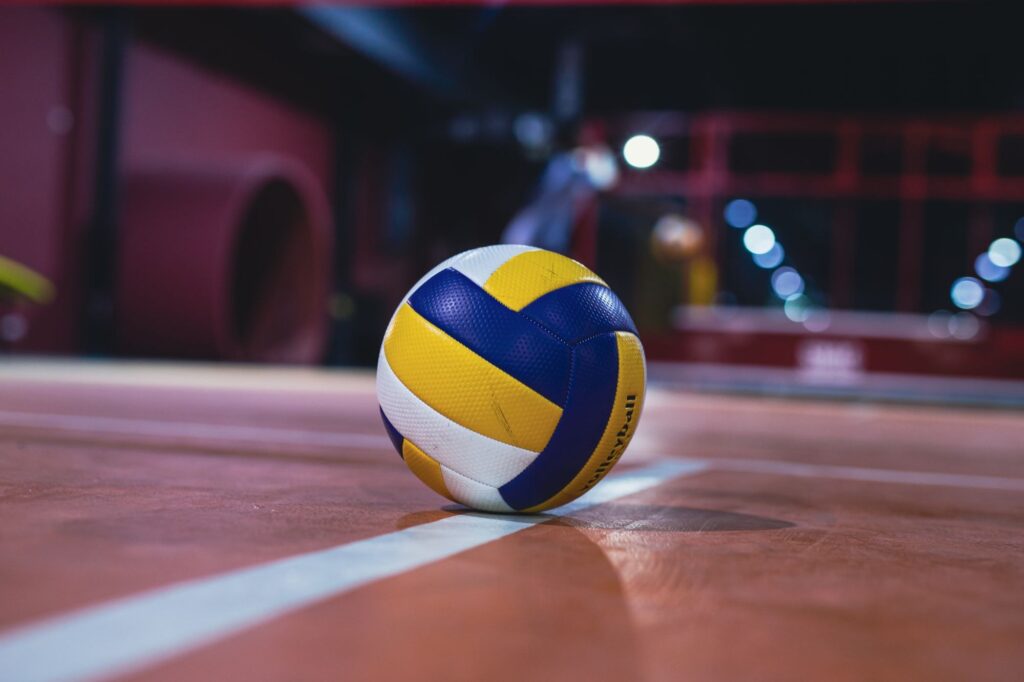 Volleyball resting on an indoor court line under arena lights